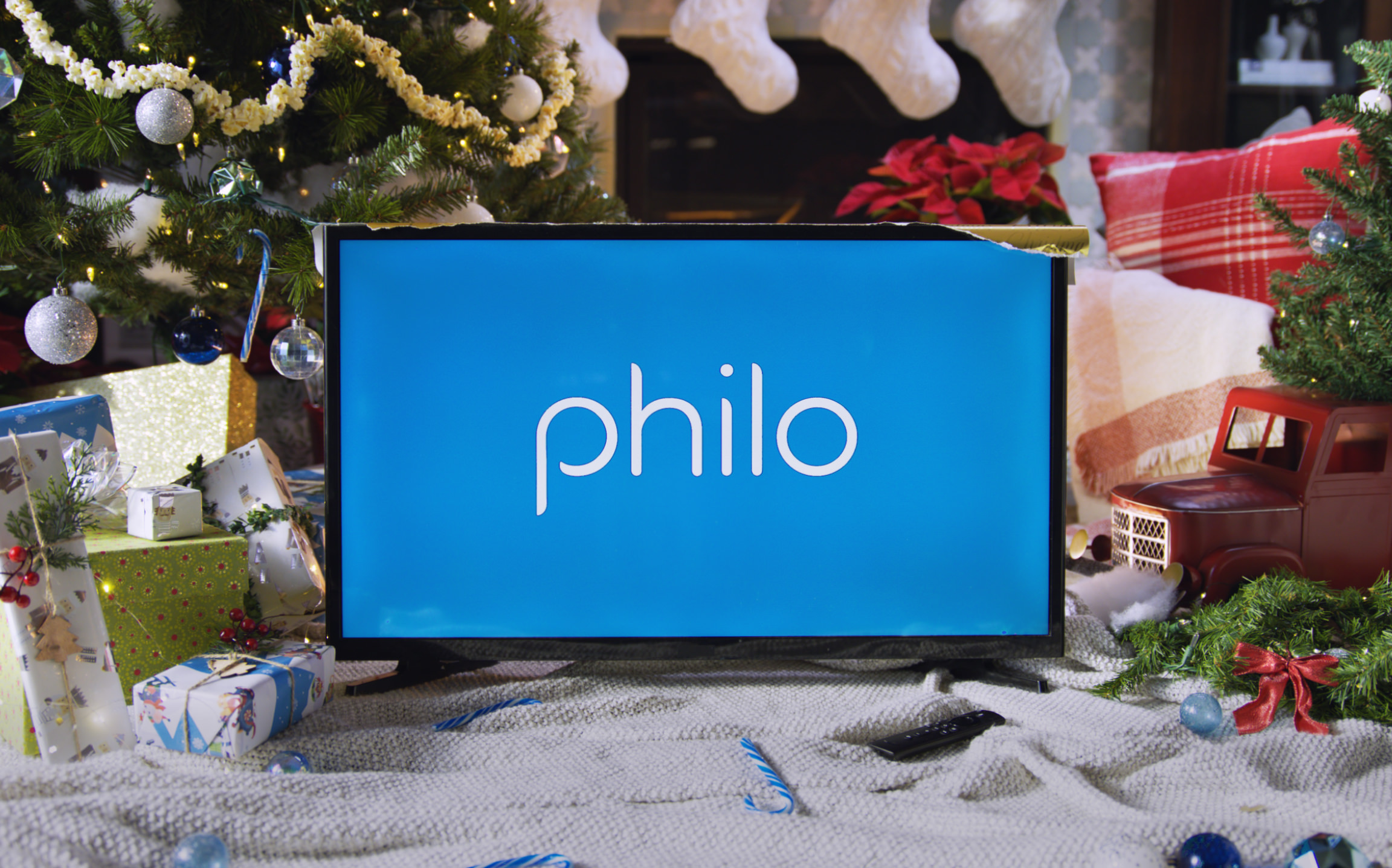A TV in front of a Christmas setting shows Philo on a TV.